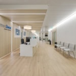 Intérieur d'un centre médical avec un comptoir d'accueil et des chaises dans un couloir lumineux.