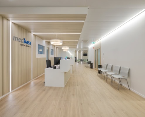 Intérieur d'un centre médical avec un comptoir d'accueil et des chaises dans un couloir lumineux.