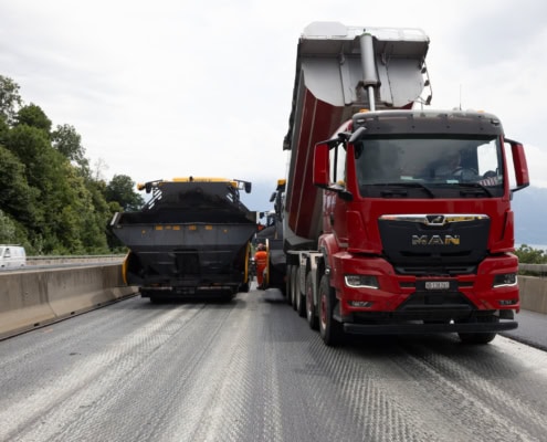 Camion de construction MAN et un véhicule de transport sur une route en cours de travaux.