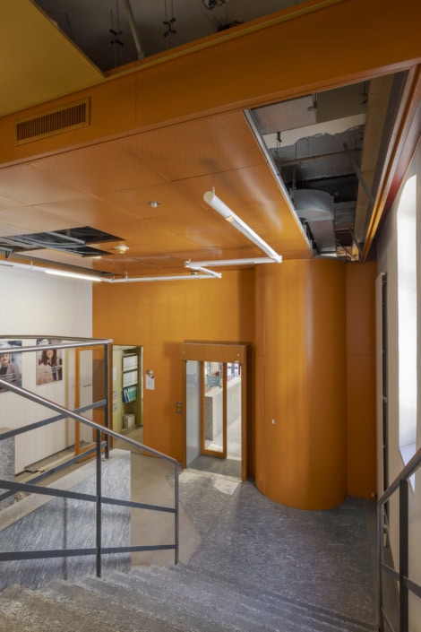 Élégantes escaliers intérieurs avec murs orange et éclairage moderne à Lausanne.