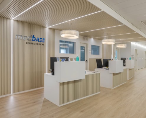 Intérieur moderne de la réception du Centre Médical Metabase avec des comptoirs blancs et des luminaires.