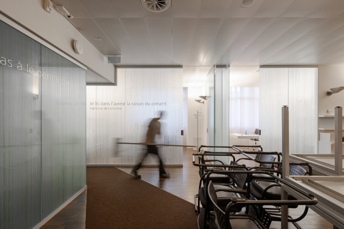 Salles d'attente modernes avec fauteuils et murs en verre translucide.