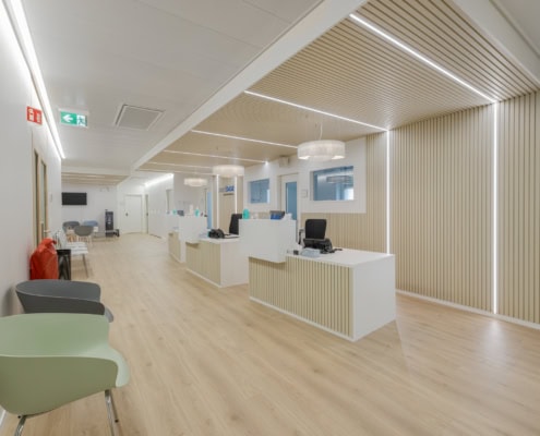 Intérieur d'un bureau moderne avec des postes de travail blancs et des chaises colorées dans un espace lumineux.