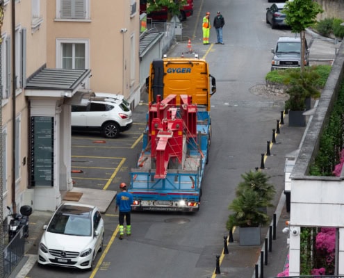 Un camion de livraison orange transportant des équipements de construction sur une route en milieu urbain.