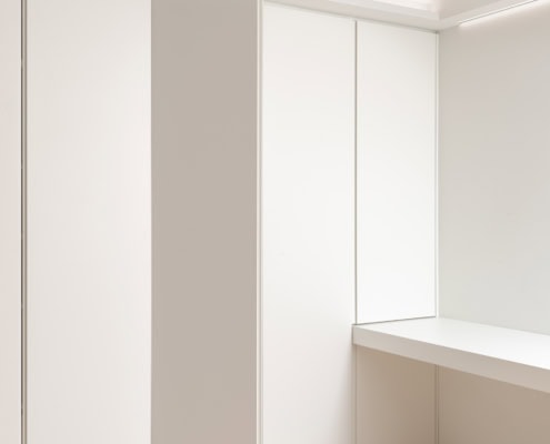 Intérieur d'une pièce avec des murs blancs et un bureau en bois clair.