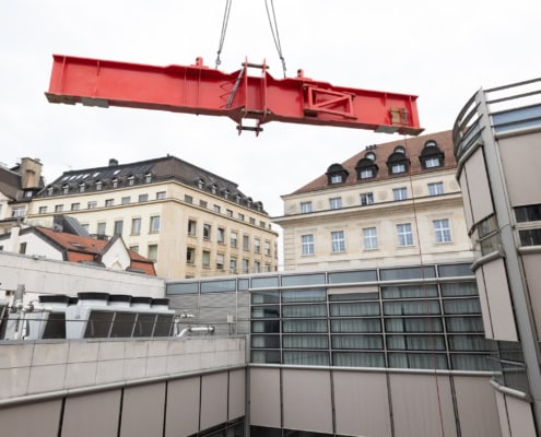 Grue rouge suspendue au-dessus d'un bâtiment dans un environnement urbain avec des structures modernes.