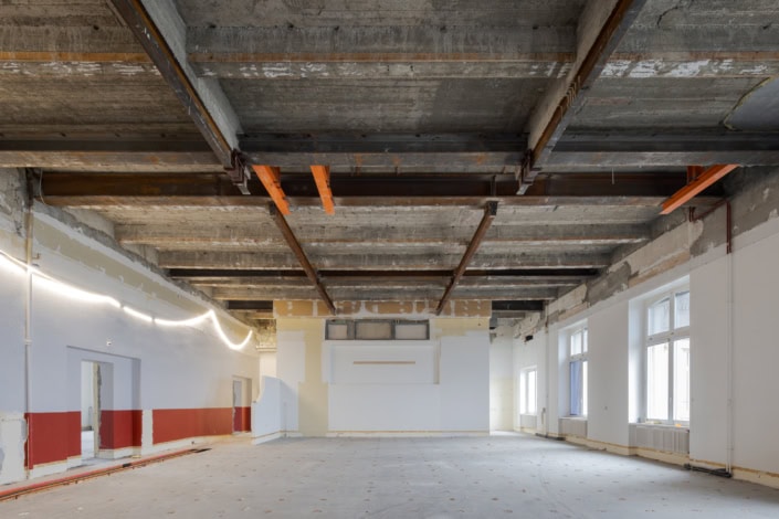 Sous-sol en rénovation avec plafond en béton nu et fenêtres lumineuses.