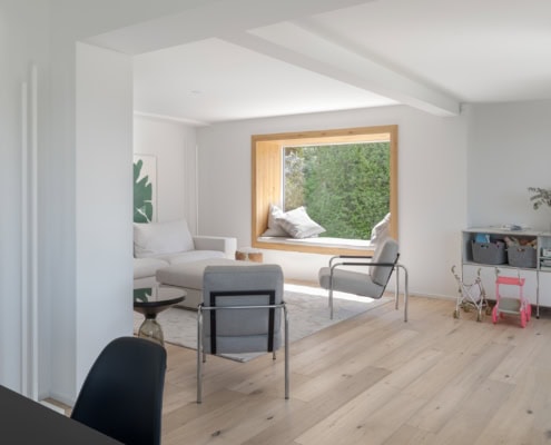 Intérieur d'une pièce moderne avec un canapé, des chaises et une grande fenêtre en bois.