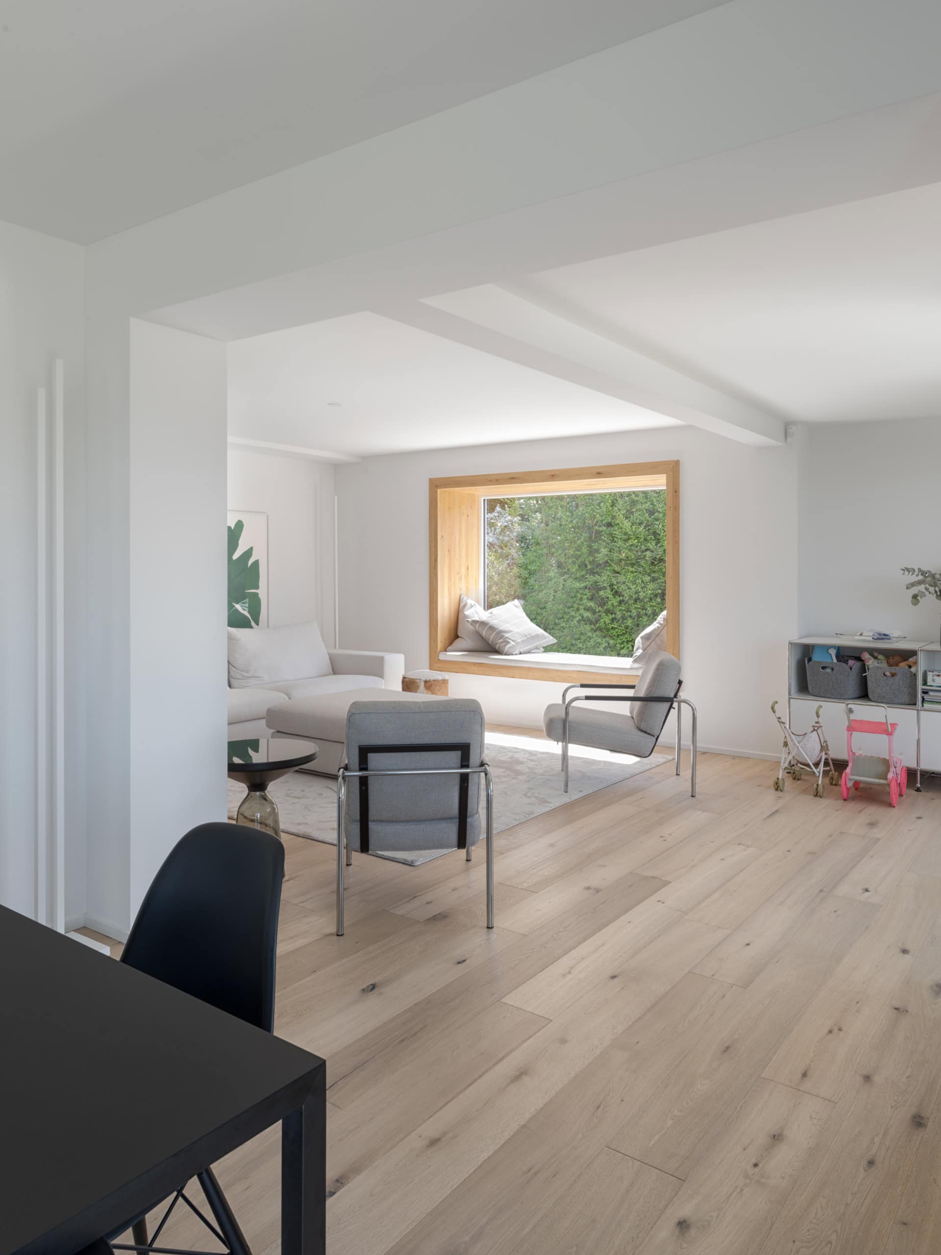 Intérieur d'une pièce moderne avec un canapé, des chaises et une grande fenêtre en bois.