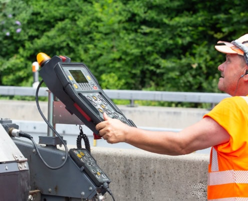 Un ouvrier en orange utilisant un panneau de contrôle sur un chantier avec des équipements de construction.