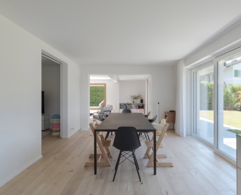 Intérieur d'une salle à manger moderne avec une table en bois et des chaises noires et blanches.