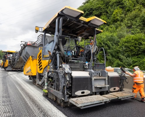 Machine de construction routière avec des travailleurs sur un chantier de route en cours.