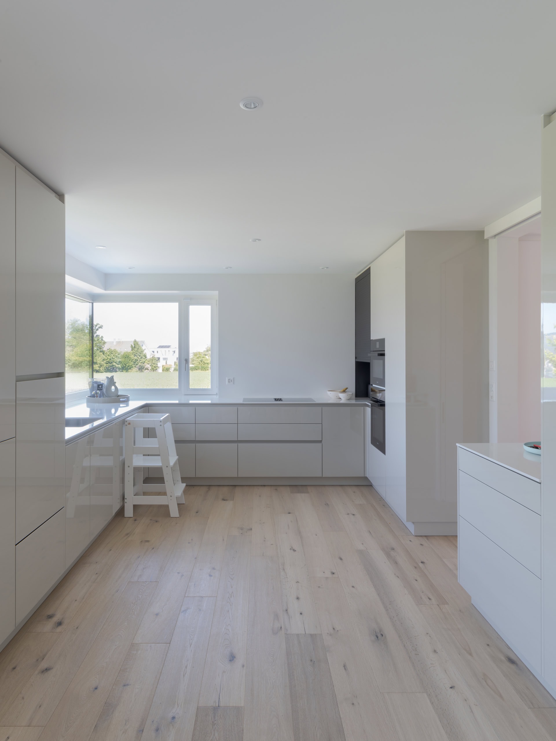 Cuisine moderne avec des meubles clairs et un plan de travail en surface lisse, éclairée par la lumière naturelle.
