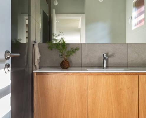 Meuble de salle de bain en bois clair avec lavabo et miroir dans un intérieur moderne.