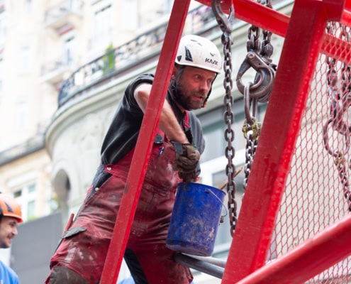 Un ouvrier de construction portant un casque et des vêtements de travail, utilisant un seau sur un chantier.