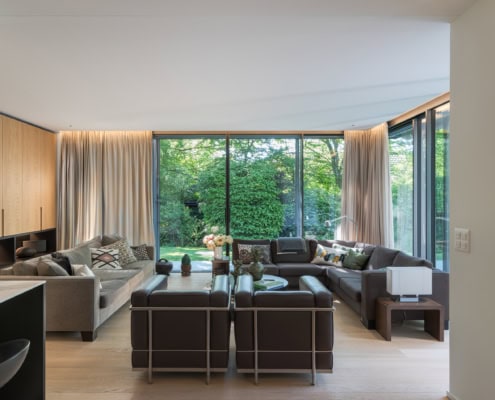 Salon spacieux avec canapés modernes et grandes fenêtres donnant sur un jardin.