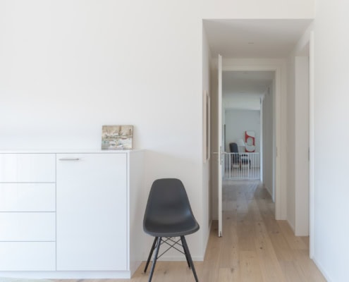 Chaise noire en plastique avec des pieds en bois dans une chambre lumineuse et minimaliste.