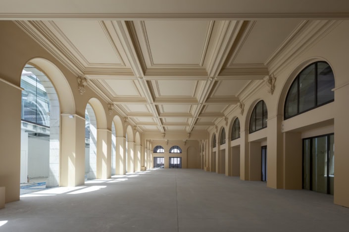 Salle intérieure lumineuse avec arches et grandes fenêtres, architecture élégante.