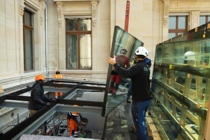 Travailleurs installant des fenêtres en verre dans un bâtiment historique à Lausanne.