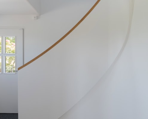 Escalier en colimaçon blanc avec une rampe en bois dans un intérieur moderne.