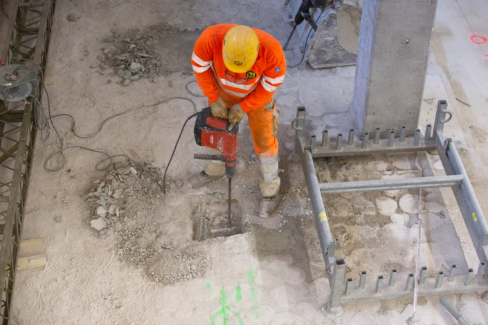 Travailleur en construction utilisant une perceuse à percussion sur chantier à Lausanne.