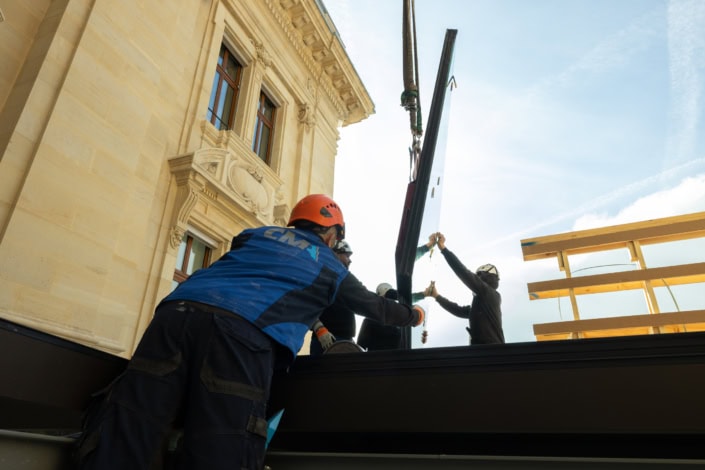 Travailleurs installant une grande vitrine lors d’un chantier architectural à Lausanne.