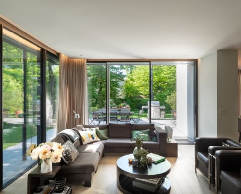 Intérieur d'un salon moderne avec un canapé, une table basse et des fenêtres en verre.