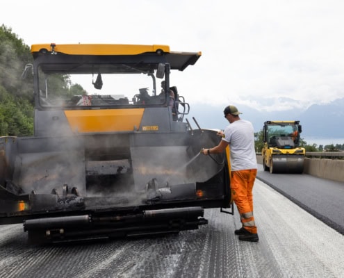 Ouvrier utilisant une machine de construction routière pour appliquer de l'asphalte sur une route.