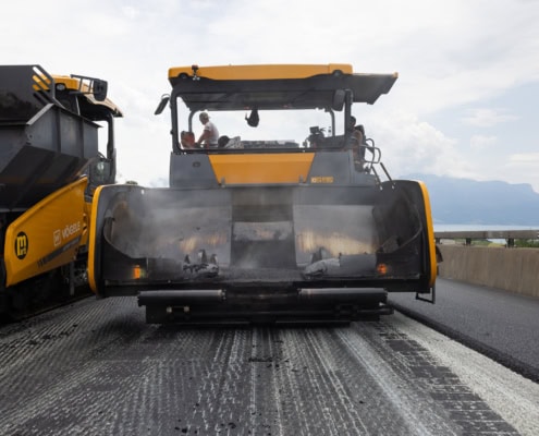 Une machine de construction routière appliquant de l'asphalte sur une route en cours de réparation.