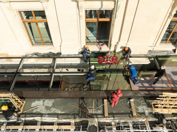 Travailleurs en construction posant un vitrage au centre d'un bâtiment ancien.