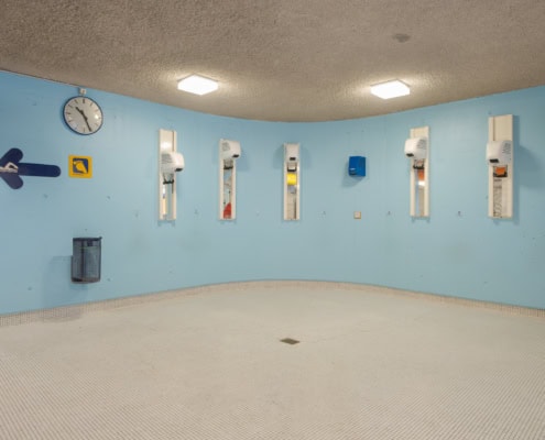 Salle de bain avec murs bleus et plusieurs appareils de séchage installés sur le mur.