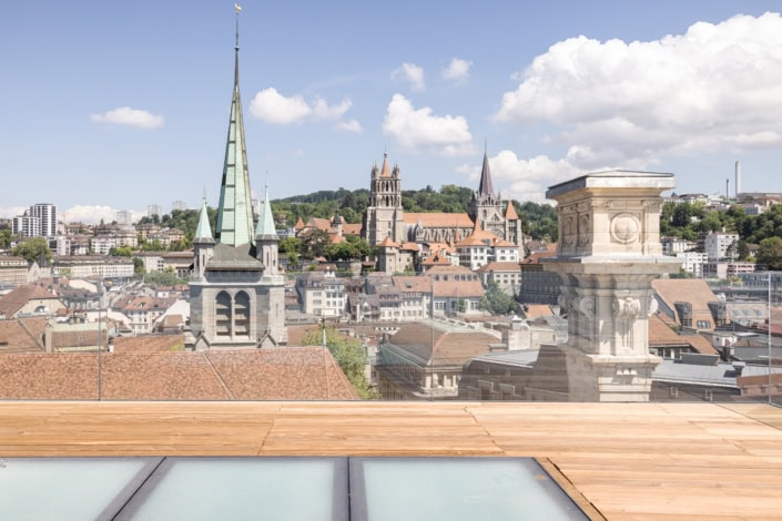 Vue panoramique de Lausanne avec des églises et bâtiments historiques, ciel bleu clair.