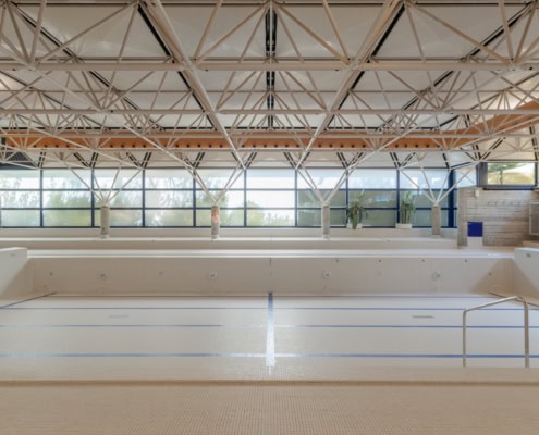 Intérieur d'une piscine vide avec des murs en carrelage et une structure en acier au plafond.