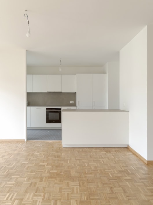 Appartement moderne avec cuisine blanche et parquet en bois clair.