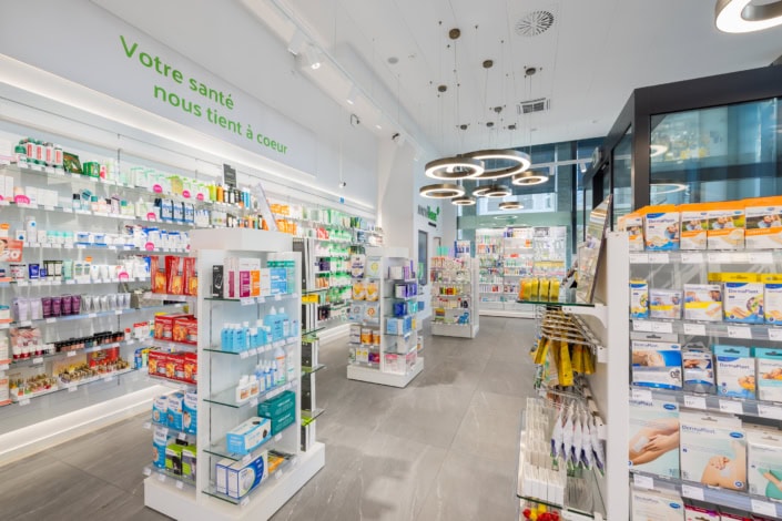 Pharmacie moderne intérieure à Lausanne, aménagement lumineux et produits variés.