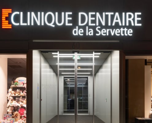 façade éclairée la nuit de la Clinique dentaire de la Servette à Genève