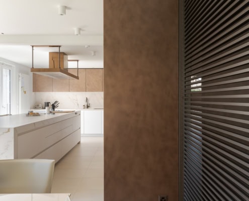 Cuisine moderne avec un mur en métal et des éléments en bois, incluant un îlot central et un éclairage suspendu.