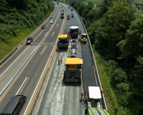 Équipe de travailleurs et machines effectuant des réparations sur une route à plusieurs voies.