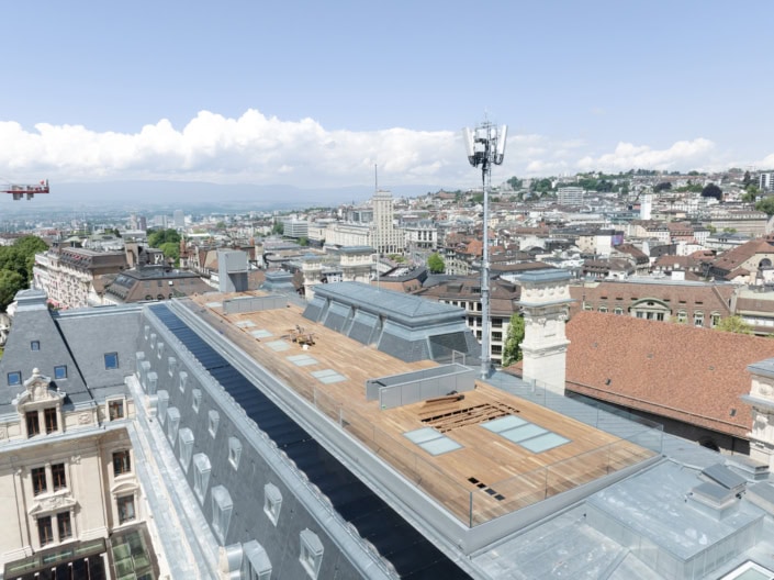 Toit en bois sur un bâtiment historique à Lausanne avec vue urbaine et ciel bleu.