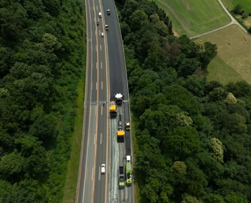 Vue aérienne de travaux de construction sur une route avec des véhicules de chantier.