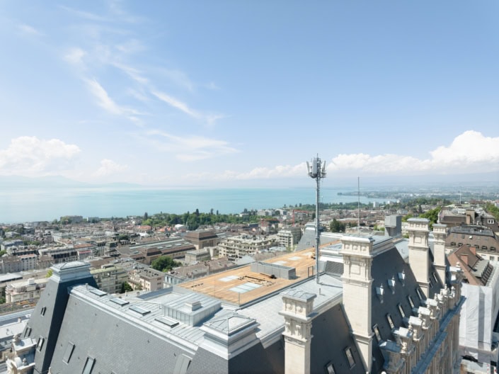 Vue panoramique de Lausanne avec le lac Léman en arrière-plan, ciel bleu et bâtiments historiques.