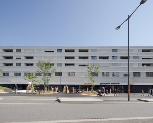 Façade d'un bâtiment moderne avec plusieurs fenêtres et un espace extérieur dégagé.