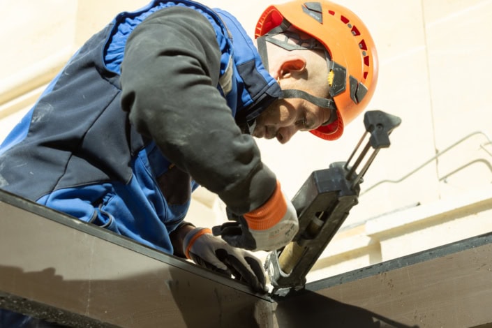 Travailleur en protection casque utilisant une visseuse électrique sur chantier.