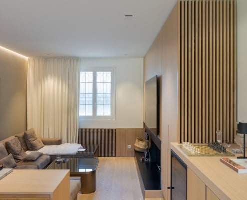 Intérieur d'un salon moderne avec un canapé gris, une table basse et des murs en bois.