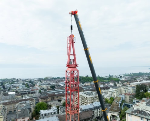 Grue rouge en train de travailler sur un bâtiment avec une vue panoramique sur la ville et le lac.