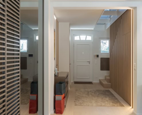 Entrée d'une maison avec un miroir, des portes en bois et un tapis au sol.