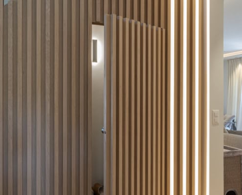 Panneau en bois avec des lattes verticales et un éclairage LED intégré sur le côté droit.