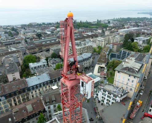 Grue rouge sur un bâtiment avec vue sur la ville et le lac en arrière-plan.