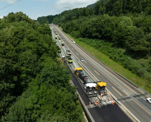 Équipe de construction effectuant des travaux sur une autoroute avec des machines et des véhicules.