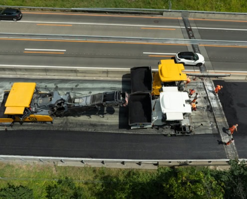 Machines de construction et ouvriers effectuant des travaux de réparation sur une route.